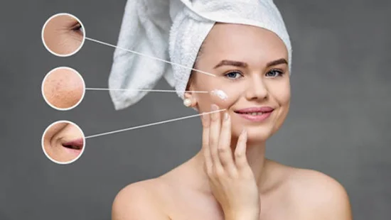 Close up of a woman applying moisturizing anti aging cream on her face to remove skin imperfection and wrinkles during her beauty routine.